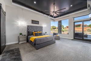 Bedroom featuring access to exterior, a barn door, a tray ceiling, and baseboards