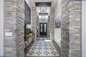 Foyer entrance featuring a towering ceiling, a chandelier, dark wood-style flooring, and french doors