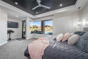 Carpeted bedroom with a tray ceiling, visible vents, baseboards, and recessed lighting