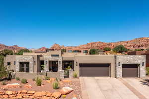 View of front of home with stucco siding, an attached garage, a mountain view, stone siding, and driveway