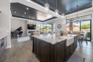 Kitchen featuring pendant lighting, a raised ceiling, a sink, and an island with sink