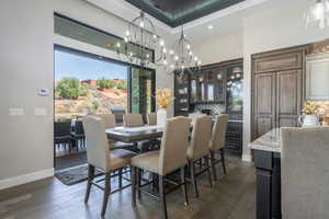 Dining space with a tray ceiling, dark wood-type flooring, visible vents, and baseboards