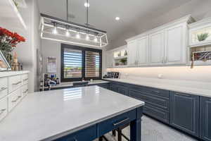 Kitchen featuring a wealth of natural light, pendant lighting, white cabinets, and light countertops