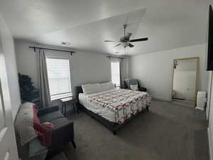 Bedroom featuring a textured ceiling, ceiling fan, visible vents, baseboards, and dark colored carpet