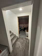 Hallway featuring carpet, stairs, and a textured ceiling