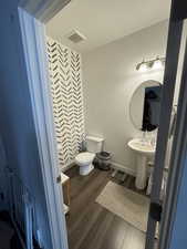 Bathroom featuring toilet, a sink, wood finished floors, visible vents, and baseboards