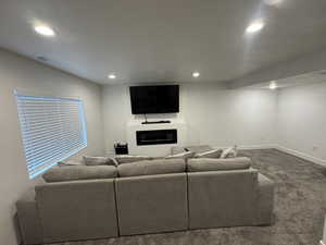 Living room with a glass covered fireplace, visible vents, carpet, and recessed lighting