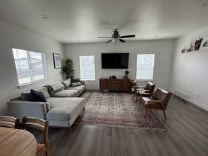 Living area with baseboards, visible vents, dark wood finished floors, and a textured ceiling