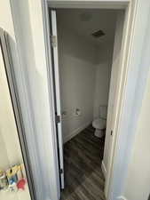 Bathroom featuring toilet, baseboards, visible vents, and wood finished floors
