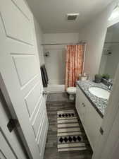 Full bathroom featuring shower / tub combo, visible vents, wood finished floors, a textured ceiling, and vanity