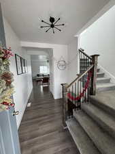 Staircase with a textured ceiling, wood finished floors, a ceiling fan, and baseboards