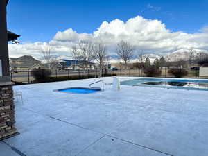 Community pool featuring a mountain view, a hot tub, and fence