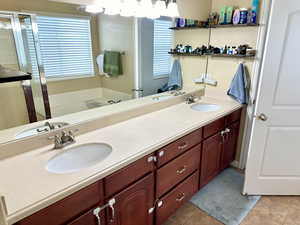 Bathroom with double vanity, a sink, and tile patterned floors