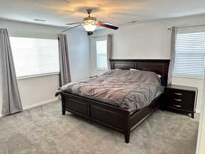 Bedroom with visible vents, ceiling fan, light carpet, and baseboards