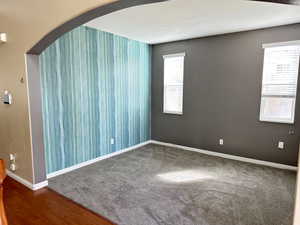 Spare room with arched walkways, baseboards, and a healthy amount of sunlight