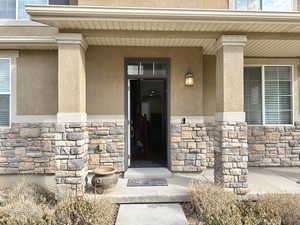 Property entrance featuring stone siding, a porch, and stucco siding