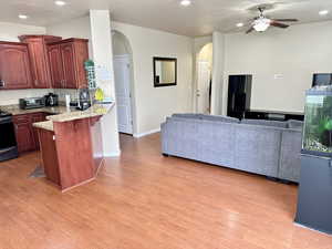 Kitchen with arched walkways, a peninsula, wood finished floors, a kitchen breakfast bar, and open floor plan