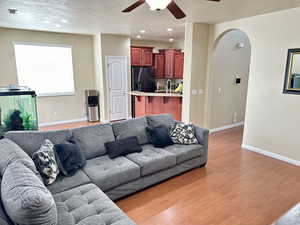 Living room with baseboards, arched walkways, a ceiling fan, wood finished floors, and recessed lighting