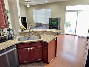 Kitchen featuring wood finished floors, a sink, open floor plan, dark brown cabinets, and dishwasher