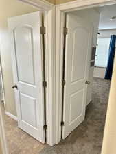 Hall with light tile patterned floors and light colored carpet