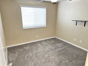 Carpeted spare room with baseboards and a ceiling fan