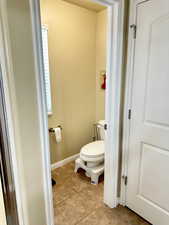 Bathroom with tile patterned flooring, baseboards, and toilet