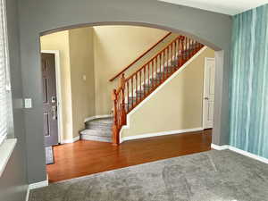 Stairway with arched walkways, carpet floors, wood finished floors, and baseboards