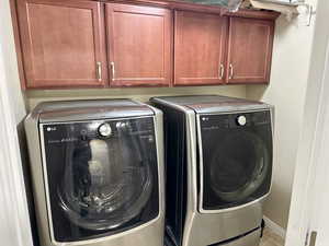 Clothes washing area with washer and dryer, cabinet space, and baseboards