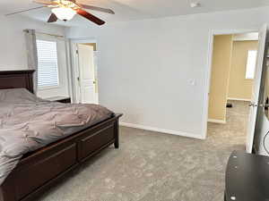 Bedroom featuring a ceiling fan, light carpet, and baseboards