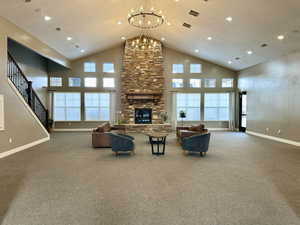 Carpeted living area with high vaulted ceiling, a fireplace, visible vents, and baseboards