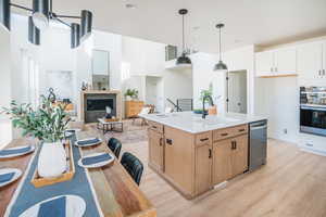 Kitchen featuring a sink, white cabinets, light countertops, appliances with stainless steel finishes, and a center island with sink