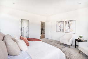 Bedroom featuring baseboards, ensuite bathroom, and light colored carpet