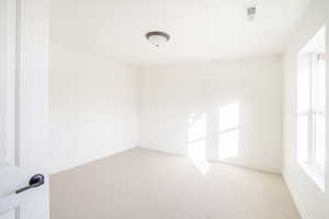 Empty room featuring light carpet, visible vents, and baseboards