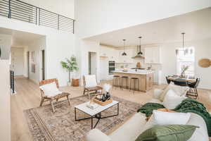 Living room featuring a high ceiling, light wood-style flooring, and baseboards