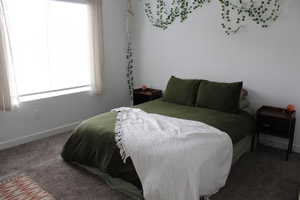 Bedroom with baseboards and dark colored carpet