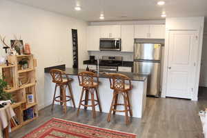 Kitchen featuring stainless steel appliances, white cabinets, a peninsula, and a breakfast bar area