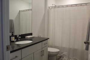 Bathroom with a shower with shower curtain, vanity, and toilet