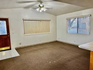 Interior space with carpet floors, a ceiling fan, a wealth of natural light, and lofted ceiling