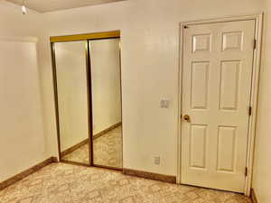 Unfurnished bedroom with baseboards, a closet, and light colored carpet