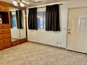 Unfurnished bedroom featuring ceiling fan, light carpet, visible vents, baseboards, and a closet