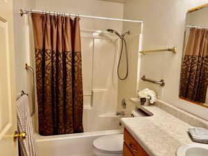 Bathroom featuring toilet, vanity, and shower / bathtub combination with curtain