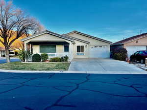 Ranch-style house featuring covered porch, driveway, an attached garage, and stucco siding