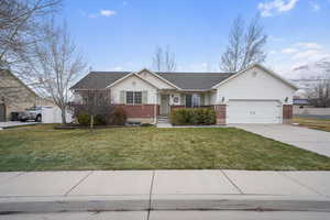 Single story home with a garage, concrete driveway, brick siding, and a front yard