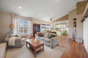 Living room featuring high vaulted ceiling, a healthy amount of sunlight, ceiling fan, and wood finished floors