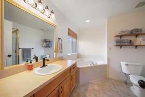 Bathroom featuring visible vents, toilet, a whirlpool tub, tile patterned flooring, and vanity