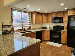 Kitchen with black appliances, brown cabinets, and a sink