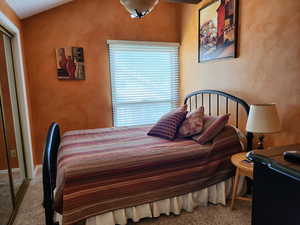 Bedroom with carpet floors and vaulted ceiling