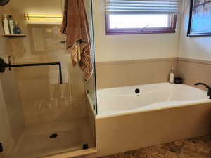 Full bath with a garden tub, stone finish flooring, and a stall shower