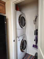 Washroom featuring laundry area, baseboards, and stacked washer / drying machine