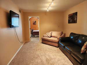 Living area with a textured ceiling, baseboards, visible vents, and light colored carpet